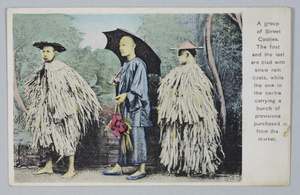 Three men posed in a photographer's studio – two wearing palm leaf raincoats and bamboo hats