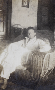 A man wearing a dressing gown, on a large rattan armchair