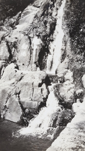 A man standing between graffitied rocks and a waterfall
