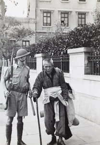 A British soldier with a blind refugee, outside the British Consulate, Shanghai, 1937