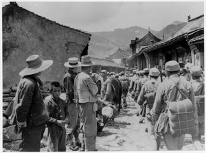 Communist troops marching through a village, watched by onlookers, West Hebei province