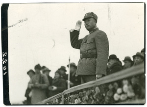 A prominent military man raising a white gloved hand in salute 