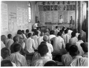 William Band teaching in a room decorated with portraits of Stalin, Marx and others
