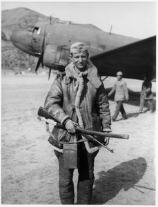 Tony Remenih with a rifle and a Japanese sword near a Douglas C-47 Skytrain (Dakota)