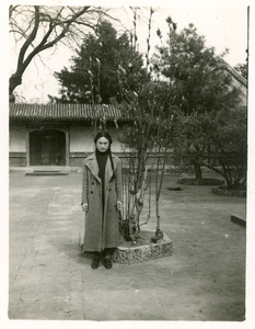 Hsiao Li Lindsay (李效黎) in a courtyard by a pruned shrub