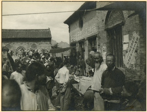 Crowded street market by a building with political slogans, South Shanxi