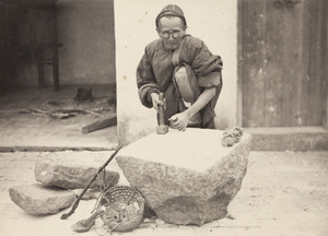 A stone mason wearing glasses, with tools