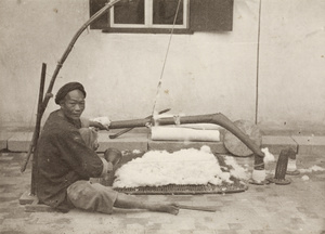 A man carding wool, posed with his tools