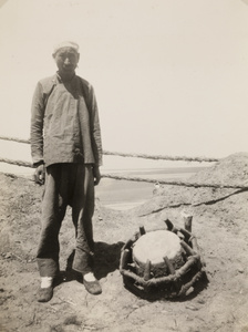 Worker with pounder used for driving piles during repair of dykes and banks on the Yellow River