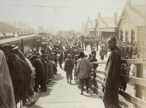 Chinese onlookers, trains, and allied troops, at Tientsin railway station