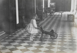 Girl with toy wheelbarrow on veranda