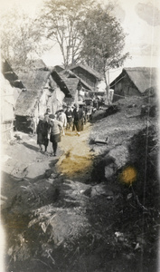 Party of Europeans walking through a village, 1920s