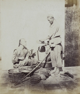 An itinerant shoe mender with tools, and a customer