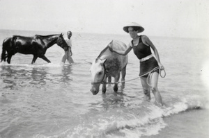 Ann Phipps and a mafoo with two horses, in the sea, Beidaihe