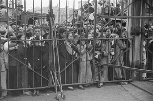 Refugees waiting by a steel gate, Shanghai