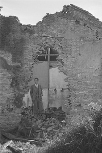 Malcolm Rosholt, framed by a ruined building, Shanghai