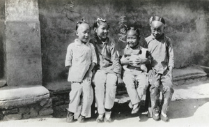 Four children sitting on a bench, with a dog