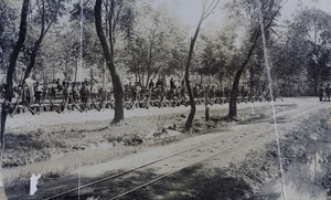 Soldiers with stack arms and kit in a row, beside a railway track