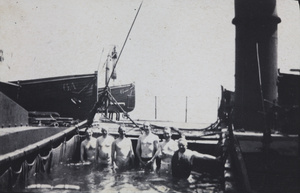 Men bathing in a canvas tub on board a ship