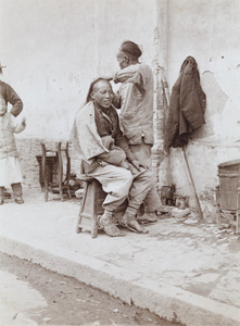 An itinerant barber dressing a man's hair