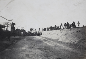 Civilians and revolutionary soldiers watching fighting from a railway embankment